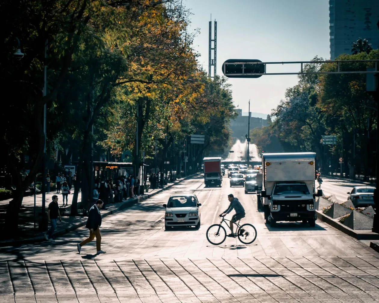 Pedestrians and a cyclist crossing a busy Mexico City street